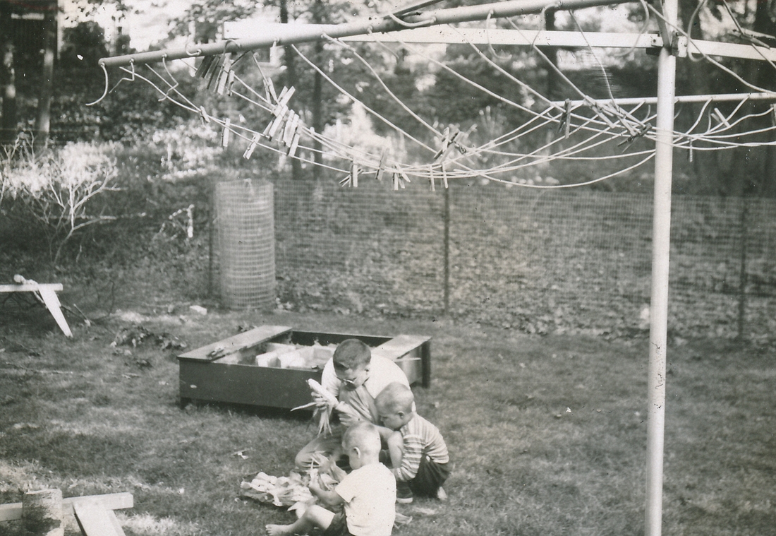 1953-08~ 2 Shucking corn, near sandbox and rotary clothesline.jpg